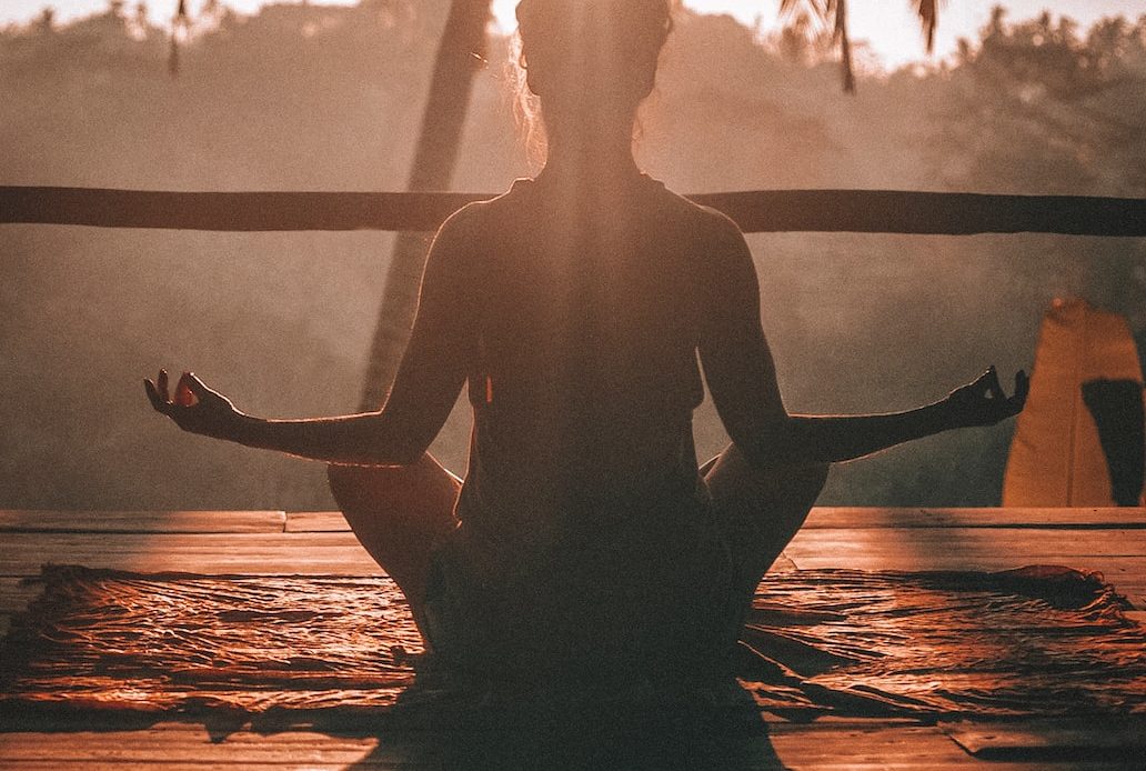 woman doing yoga meditation on brown parquet flooring